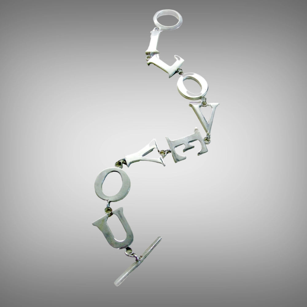 A silver letter-link chain bracelet spelling out 'I LOVE YOU' in a diagonal layout, featuring a toggle clasp, handmade from lost wax carving Tg-Jewellery