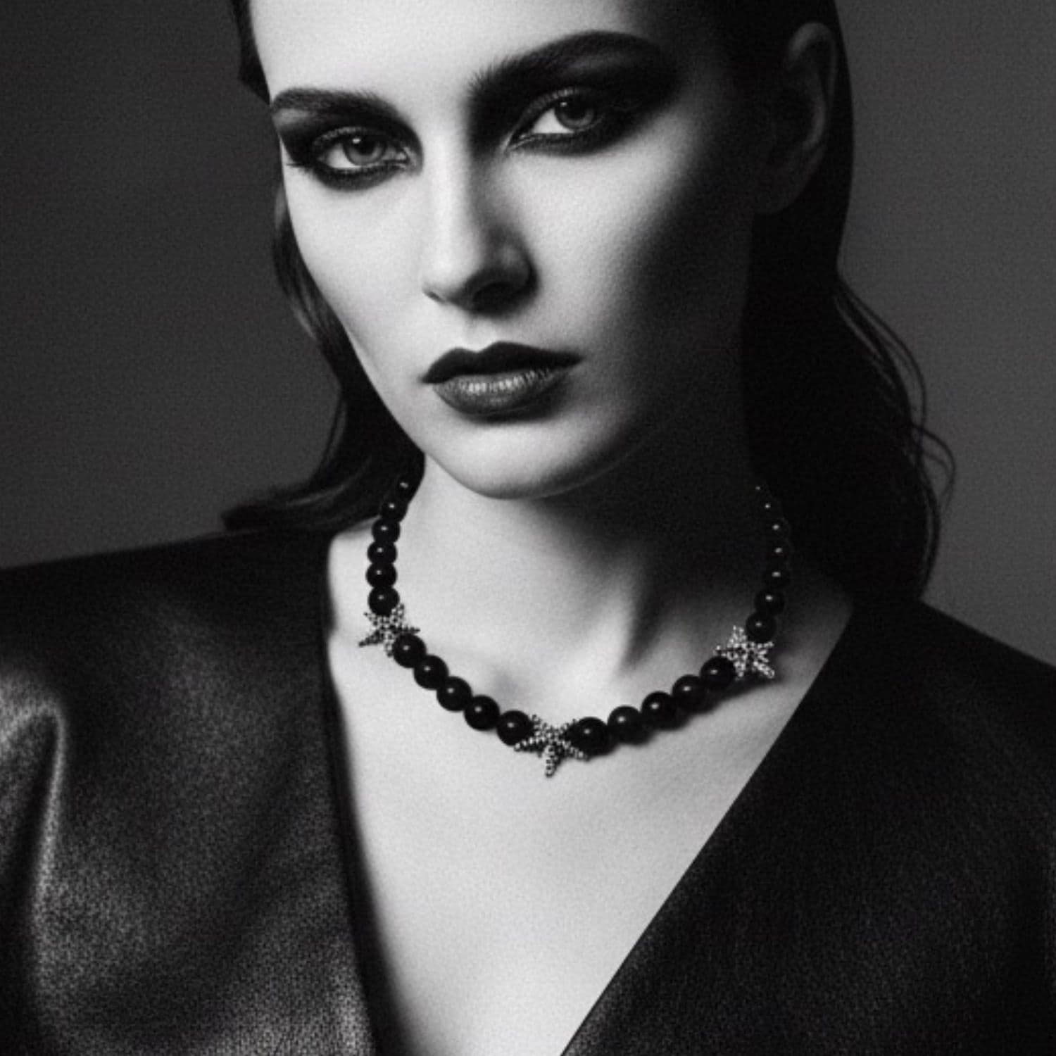 Black and white portrait of a woman wearing a necklace with a dark background