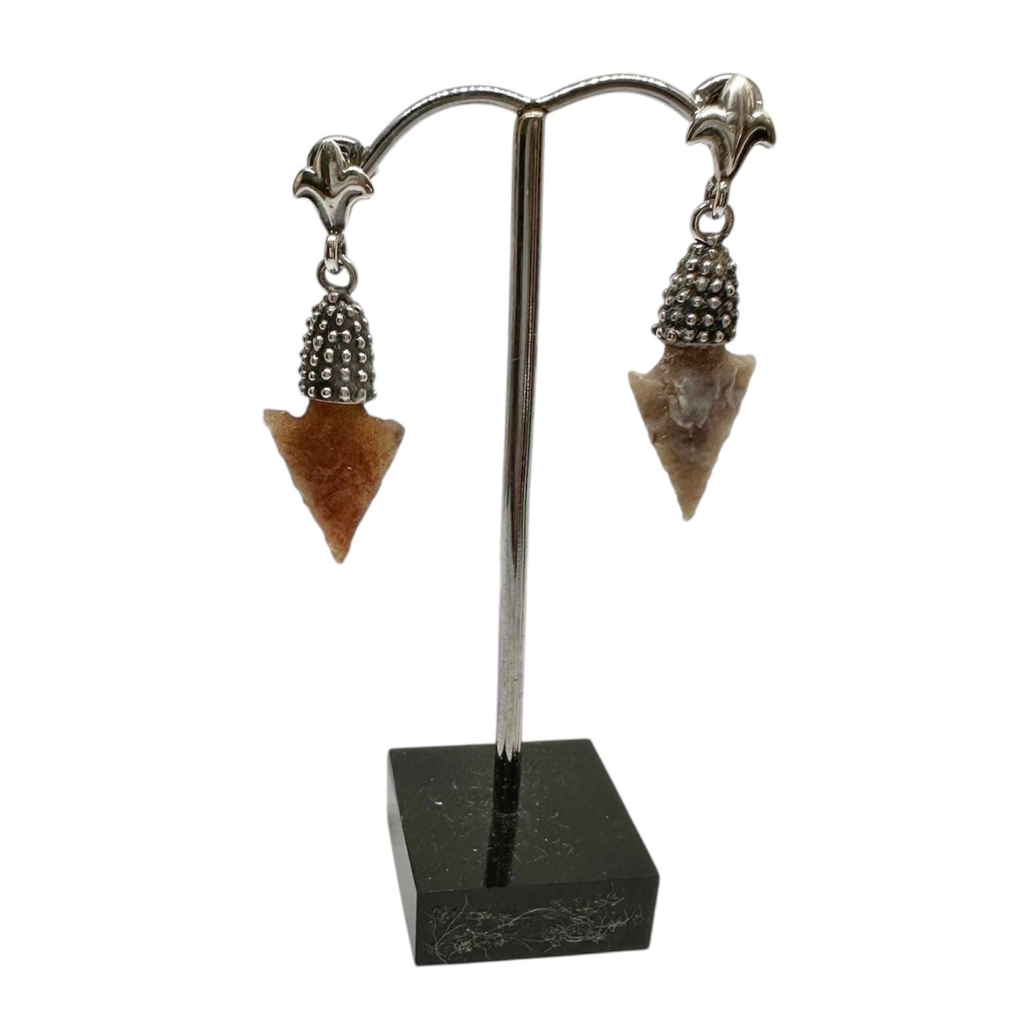 Pair of arrowhead-shaped earrings on a stand with a white background