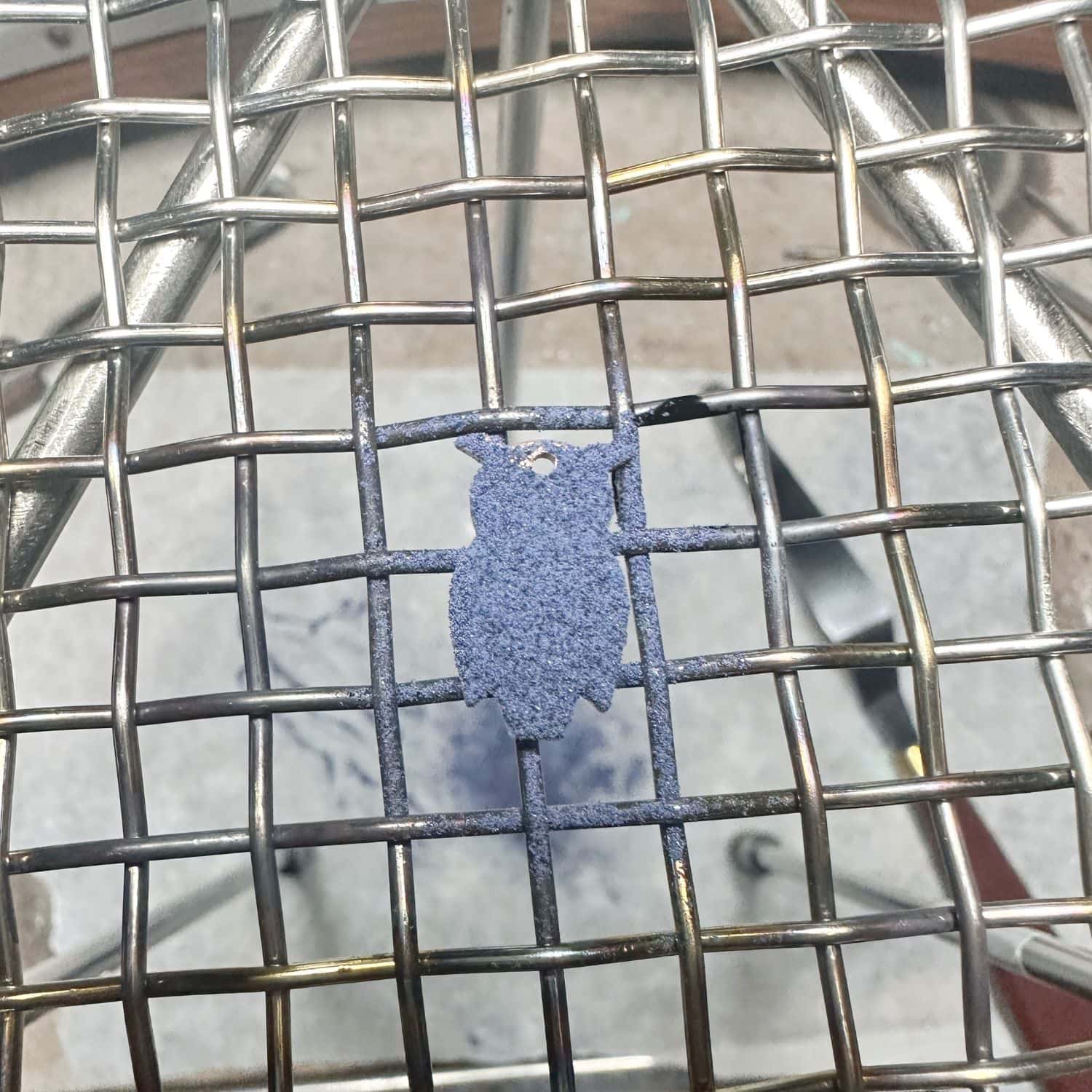 Owl brass charm coated in blue vitreous enamel powder before torch firing, TG Jewellery Cornwall