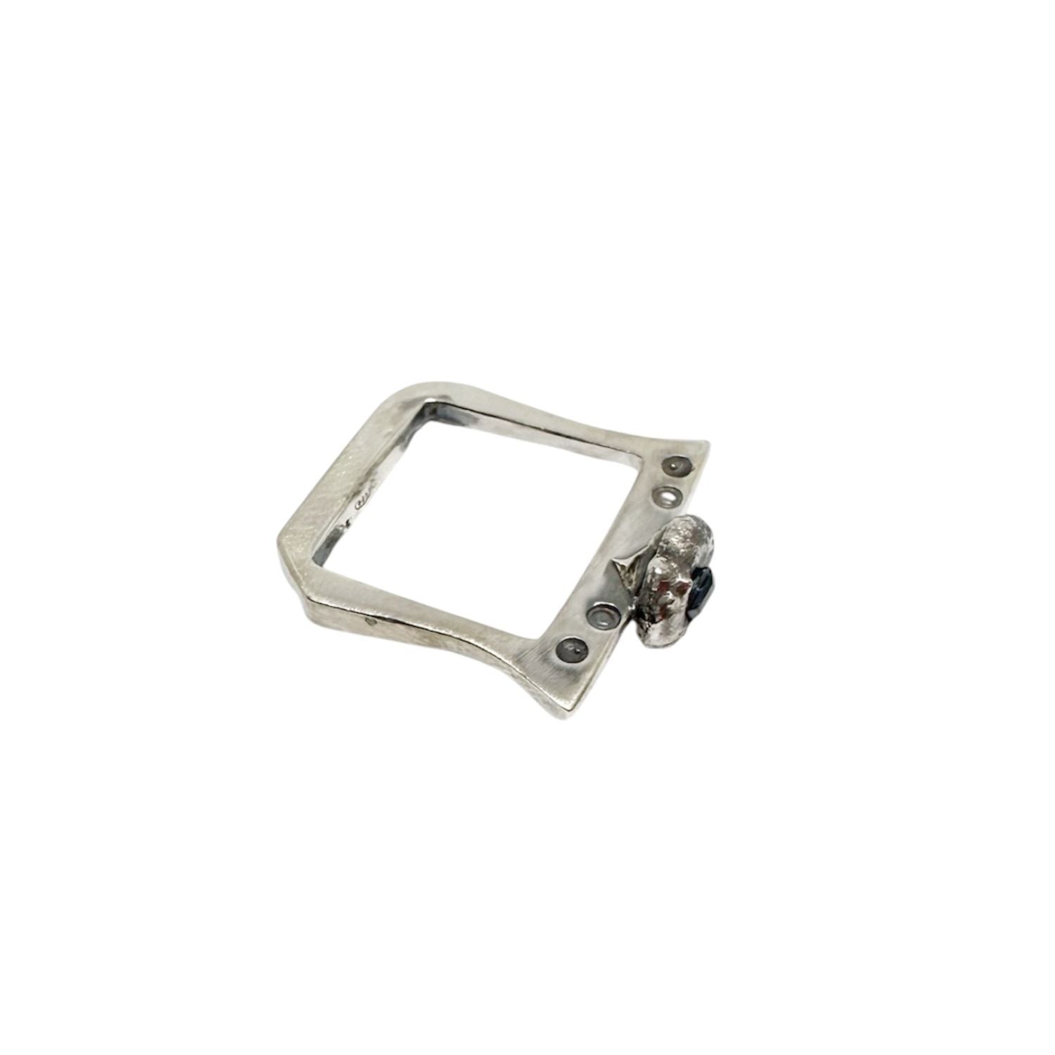 Handcrafted recycled sterling silver ring with angular band and molten pebble setting holding a 3.5mm square sapphire, partially emerging from the surface - Tg-jewellery By Tamara Gervasio