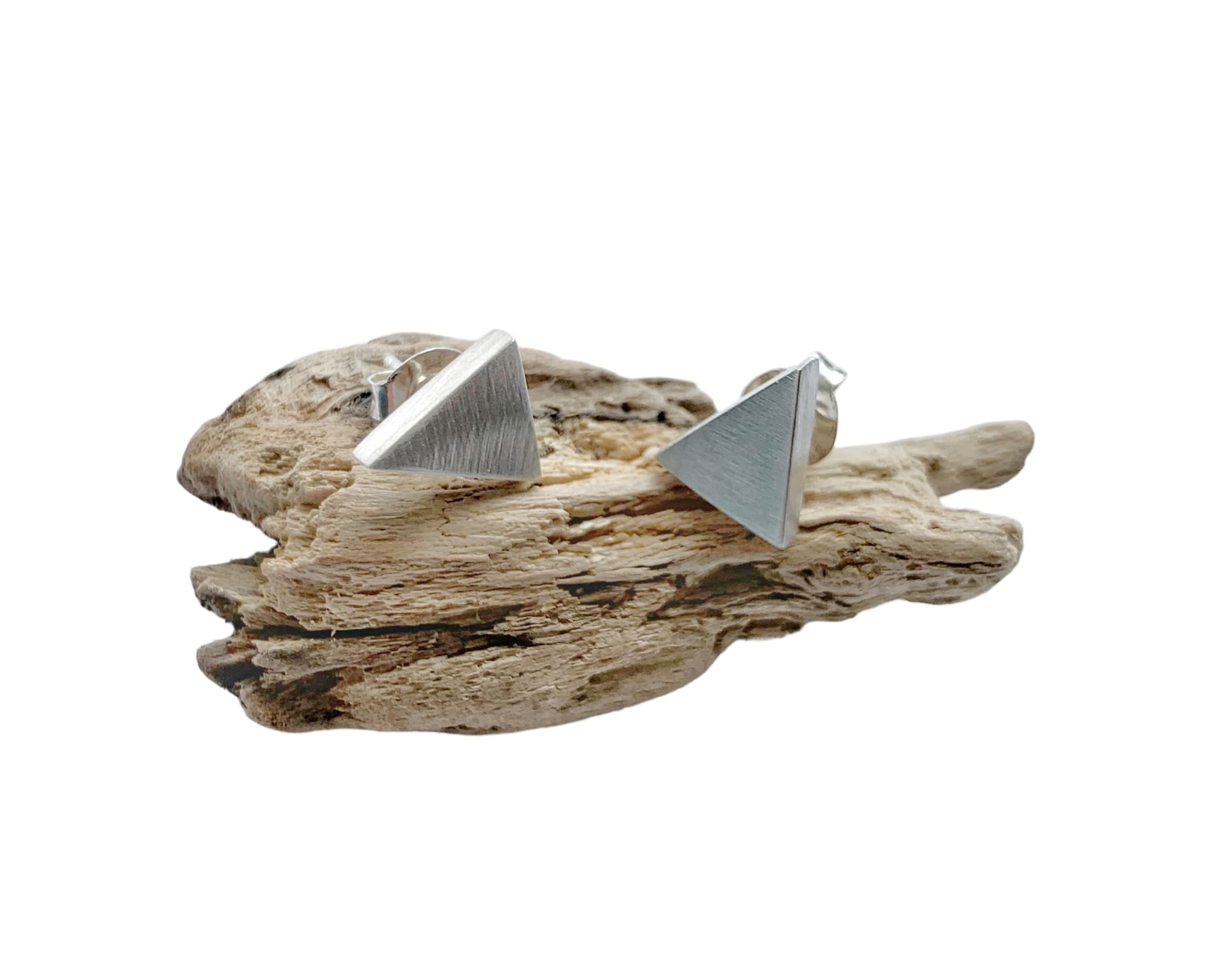 Close-up of sterling silver 925 triangle stud earrings showing geometric form and satin surface